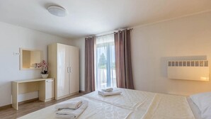 Ein Hotelzimmer mit Bett, Schreibtisch, Kleiderschrank, Spiegel und einem Fenster mit Vorhängen.