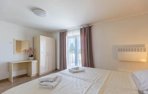 A hotel room with a bed, a desk, a wardrobe, a mirror, and a window with curtains. - House in city center of Rovinj (Rovinj)