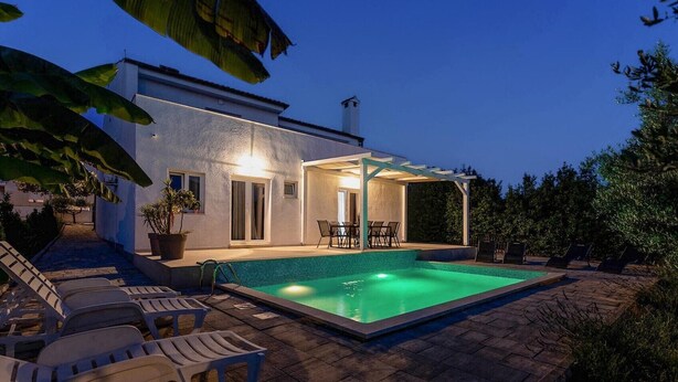 Ein Haus mit Swimmingpool, Sitzgelegenheiten im Freien und einer überdachten Terrasse.