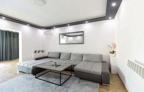 A modern living room with a sectional sofa, a coffee table, a large mirror, and a potted plant. - House in city center of Rovinj (Rovinj)