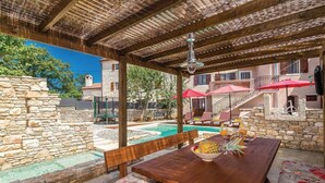 A wooden outdoor dining area with a pool, stone walls, and a covered seating area. - Holiday house in a peaceful village (Svetvincenat)