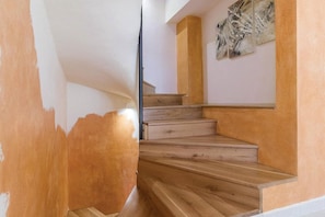 Eine Treppe mit Holzboden und Geländer, die zu einer Zwischenebene mit einem an der Wand befestigten Kunstwerk führt.
