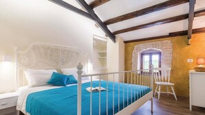 A bedroom with a white metal bed frame, a blue bedspread, a white nightstand, a white chair, and a small desk with a lamp. - Holiday house in a peaceful village (Svetvincenat)