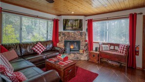 Un interior de cabaña acogedor con chimenea, sofá de cuero y pared de piedra.