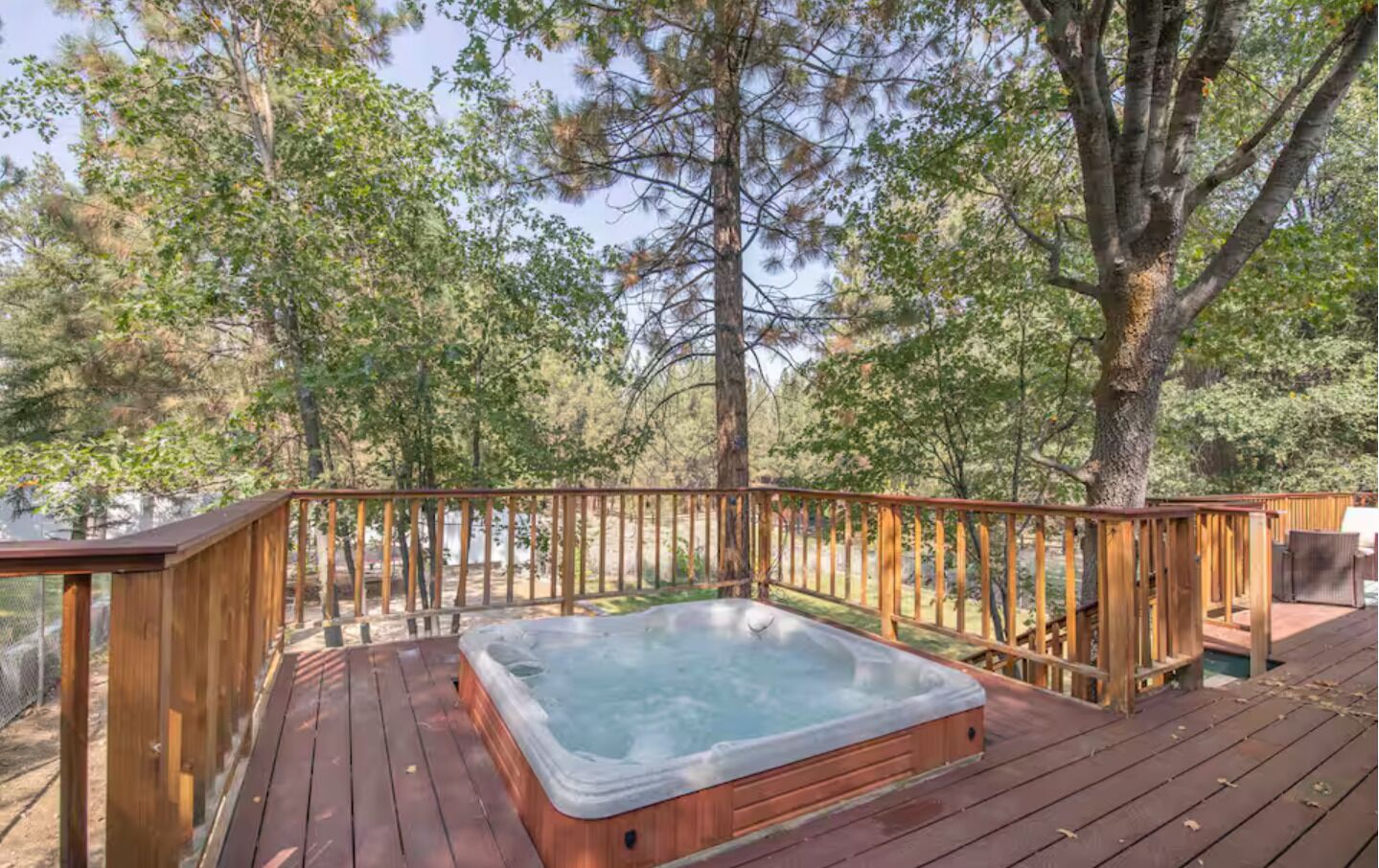 A hot tub on a wooden deck surrounded by trees.