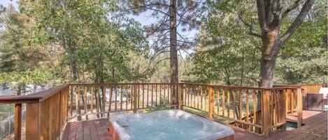 A hot tub on a wooden deck surrounded by trees.