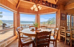 Ein Essbereich mit Holzboden, einem runden Tisch und Stühlen, großen Fenstern mit Seeblick und Bergblick sowie einem Deckenventilator.