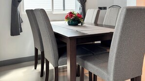 A dining area with a table, chairs, and a window with curtains. - Your ultimate modern escape awaits at NS House. (Khlong Hae Subdistrict, Hat Yai District)