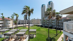 Un patio de hotel con edificios de varios pisos, palmeras y zonas de estar al aire libre.