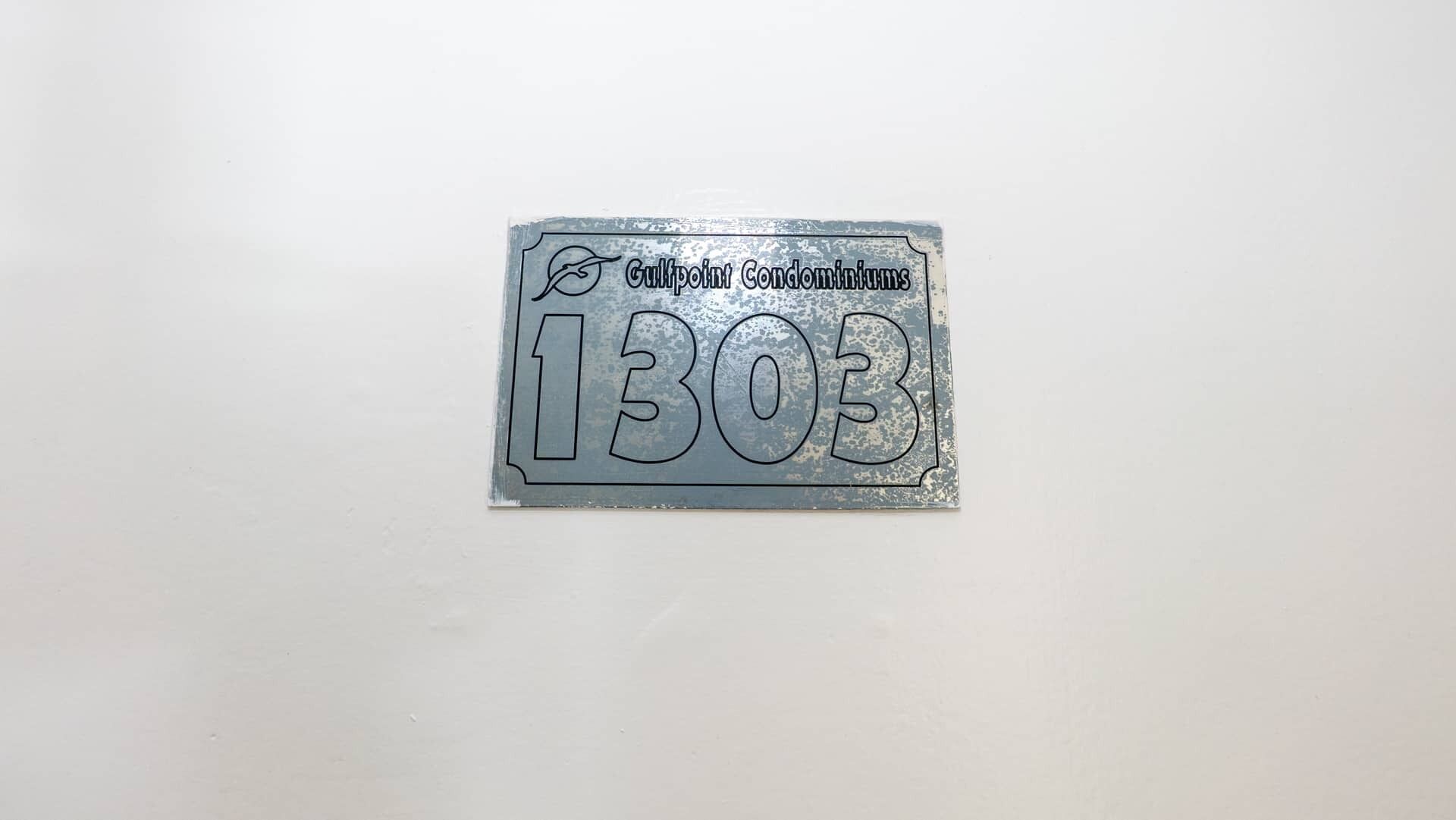 Une plaque métallique portant l’inscription « Gulfpoint Condominiums 1303 » et un petit logo.