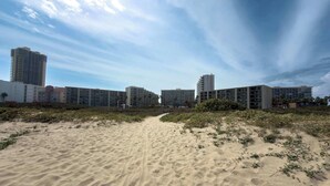 Een strandhotel met meerdere hoge gebouwen, een zandstrand en een heldere lucht.