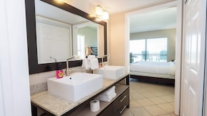 Ein Hotelbadezimmer mit zwei Waschbecken, einem großen Spiegel und Blick auf einen Balkon mit Stühlen.