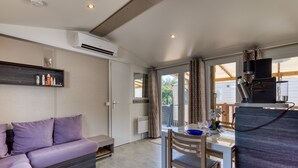 Uma cozinha compacta moderna com fogão embutido, uma área de refeições com mesa e cadeiras, um sofá e uma janela grande com cortinas.