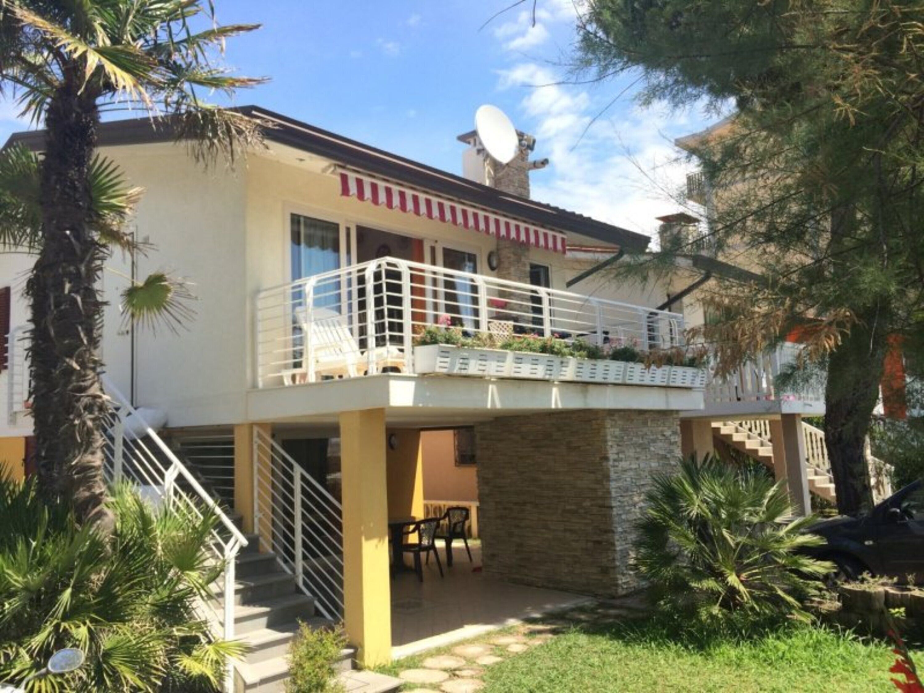 Un immeuble de deux étages doté d’un balcon, d’une antenne parabolique et d’un escalier menant à l’étage supérieur.