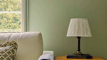 A room with a sofa, a lamp, a framed picture, and a bookshelf.