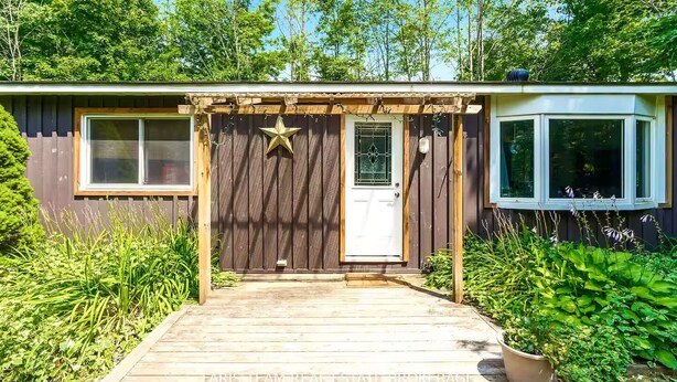 Una terraza de madera que conduce a una casa con una decoración de estrella, una puerta blanca y una ventana.