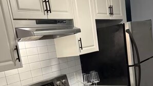 Una cocina con armarios blancos, estufa de acero inoxidable y refrigerador.