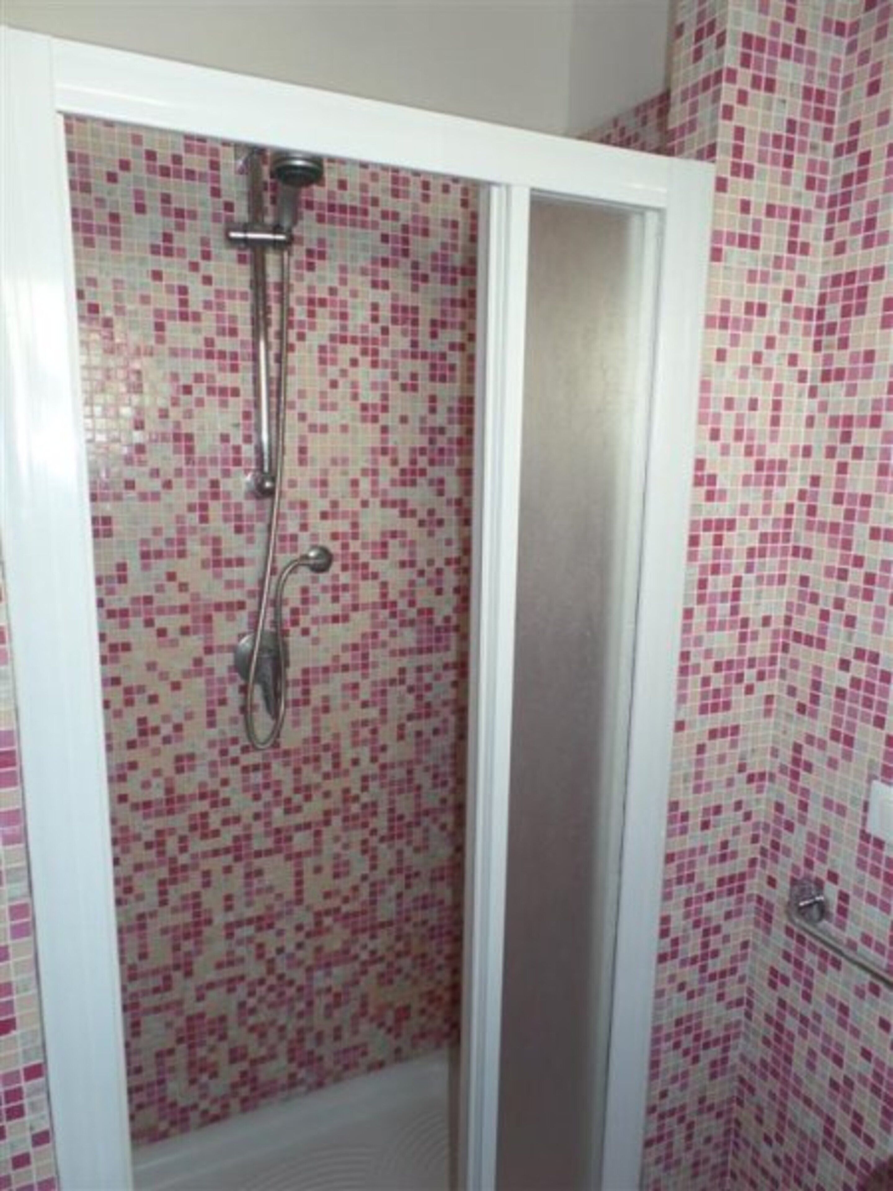 Een douche met een betegelde wand en een witte omlijsting.
