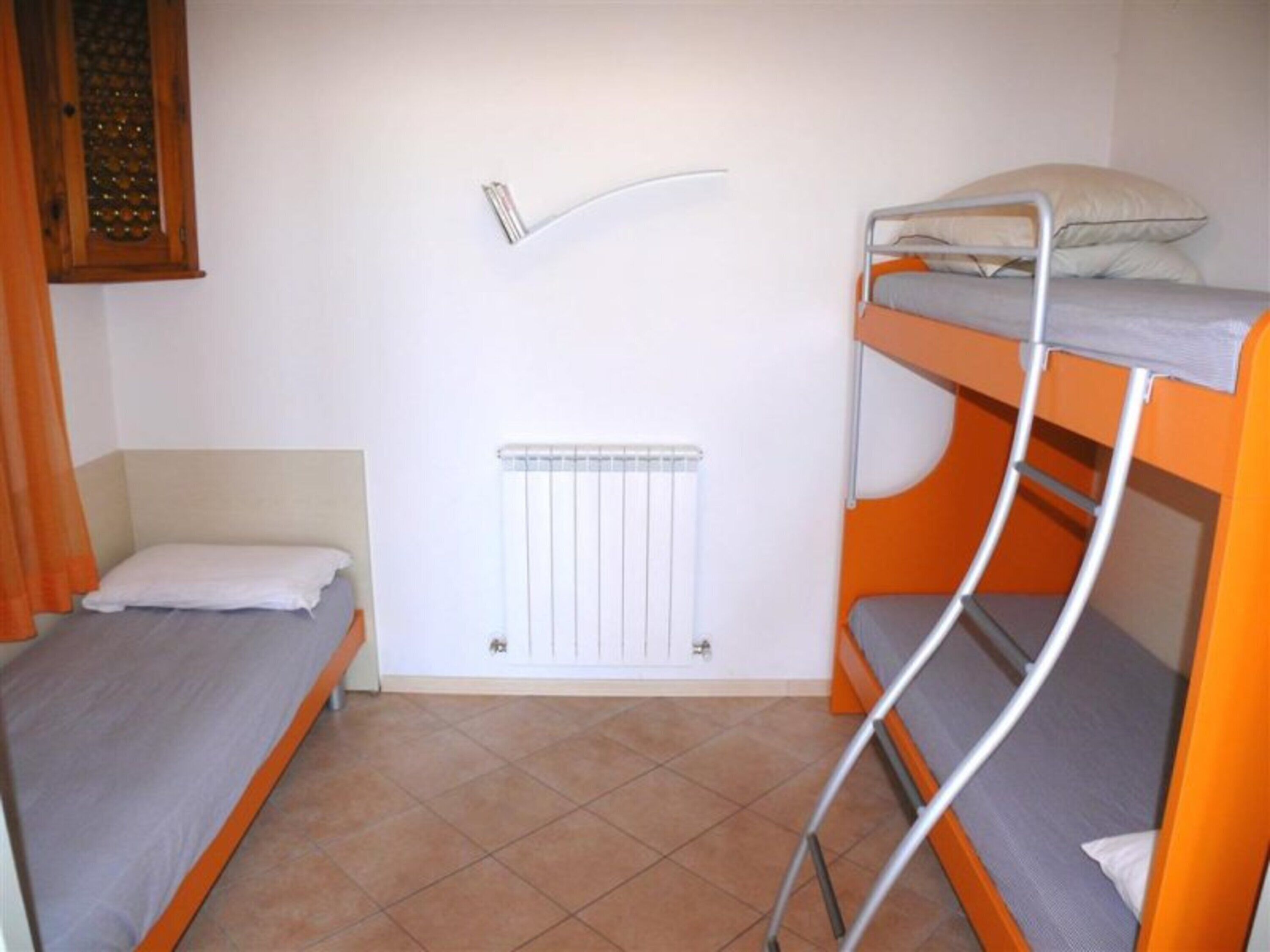 A room with two bunk beds, a radiator, and a window with a curtain.