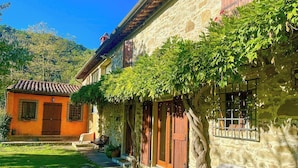 A stone building with a tiled roof, a small garden, and a white chair outside. - Farmhouse with pool 3 km from Sansepolcro (Sansepolcro)