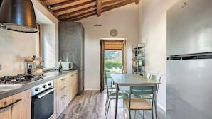 A kitchen with a wooden countertop, a stove, a microwave, and a refrigerator. There is a dining table with chairs and a view of the outdoors through a door. - Farmhouse with pool 3 km from Sansepolcro (Sansepolcro)
