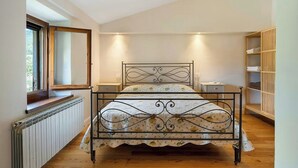 A bedroom with a bed, bedside tables, a radiator, a window, and a built-in wardrobe. - Farmhouse with pool 3 km from Sansepolcro (Sansepolcro)