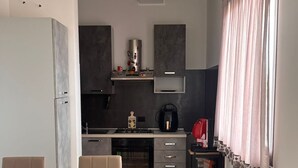 Une cuisine moderne avec un coin repas, comprenant un four encastré, une cuisinière à gaz et une machine à café.