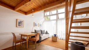 Une pièce chaleureuse avec un plafond en bois, un lit, une table avec des chaises et une fenêtre avec des rideaux.