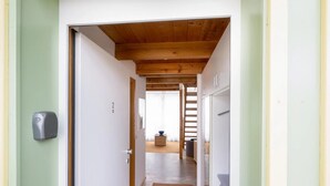 Un couloir avec un plafond en bois, une porte portant un numéro et une petite table sur laquelle se trouve un bol.