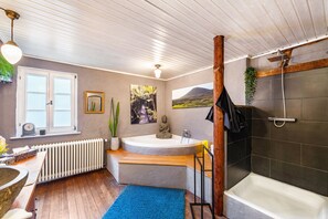 Ein Badezimmer mit Badewanne, Dusche und einem Fenster mit Bergblick.