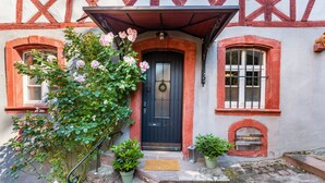 Une maison traditionnelle à colombages, avec une porte bleu foncé, un petit porche et des plantes en pot.
