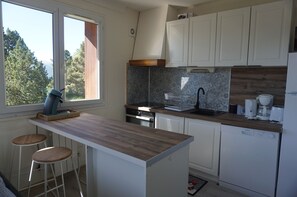 Eine kleine Küche mit Holztischplatte, weißen Schränken, einem eingebauten Backofen und einem Geschirrspüler.