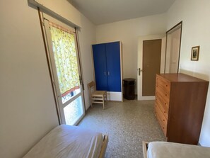 A bedroom with a bed, a dresser, a wardrobe, and a door. - Holiday Home With Garden Close to the Beach (San Michele al Tagliamento)