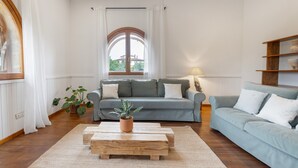 A living room with a sofa, a coffee table, a lamp, and a window with curtains.