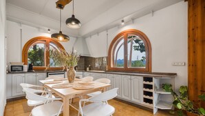 A modern kitchen with white cabinets, a wooden dining table, and white chairs.