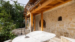 A stone building with a marble table under a wooden pergola.