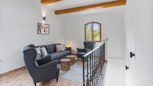 A living room with a sofa, armchairs, a small table, a window, and a staircase. - Modern holiday home with Wi-Fi, mountain view, air conditioning – Côte d’Azur, 4 guests (Roquebrune-sur-Argens)