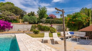 A swimming pool with stone tiles, two lounge chairs, a sofa with cushions, and a pergola with a hanging light fixture. - Modern holiday home with Wi-Fi, mountain view, air conditioning – Côte d’Azur, 4 guests (Roquebrune-sur-Argens)