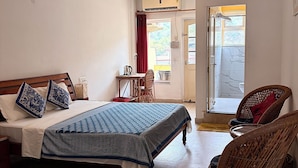 Un dormitorio con cama, ventilador de techo, ventana, puerta y una silla de mimbre.