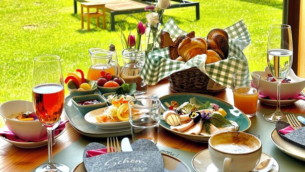 A table set for breakfast with a view of a lake and forest. - Genussgasthof Feidig (Velden am Worther See)
