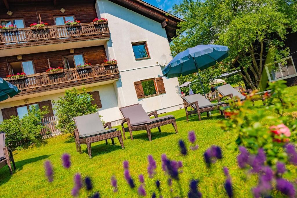 Un immeuble à plusieurs étages doté de balcons, d’un espace extérieur aménagé pour s’asseoir et d’un jardin.