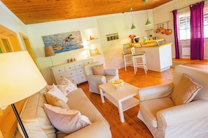 En hyggelig stue med en sofa, et sofabord og et billede af ænder på væggen.