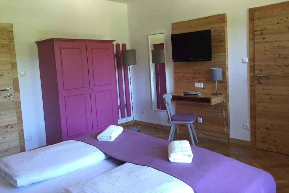 A room with two beds, a desk, a chair, a TV, and a wardrobe.
