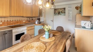 Eine Küche mit Holzausstattung, einem Esstisch mit Platzsets und Pendelleuchten.