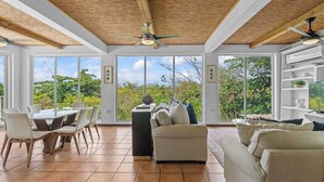 A spacious room with a dining table, chairs, a sofa, and a ceiling fan.