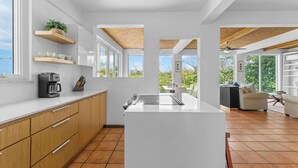 A modern kitchen with a central island, wooden cabinets, and built-in shelves.