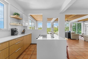 A modern kitchen with a central island, wooden cabinets, and built-in shelves. - Villa Serenidad | Oceanview Pool Retreat (Rincón)
