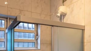 Une salle de bain avec un espace douche, une fenêtre et un porte-serviettes.