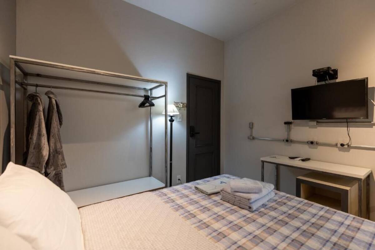 A hotel room with a bed, a desk, a TV, and a wardrobe.