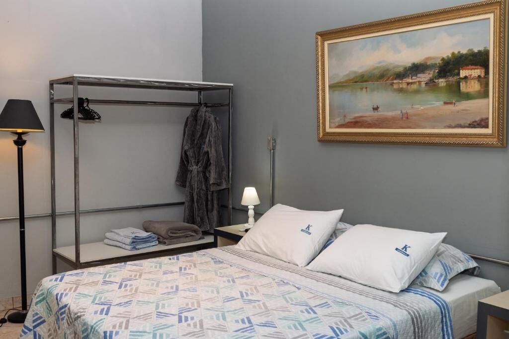 Un dormitorio con una cama, un armario metálico, una lámpara, un cuadro y vistas a un lago.